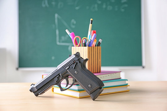 School Stationery And Gun On Table In Class