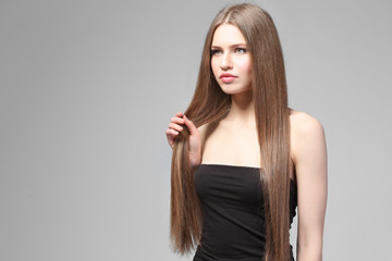 Attractive young woman with beautiful long hair on light background