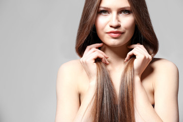 Attractive young woman with beautiful long hair on light background