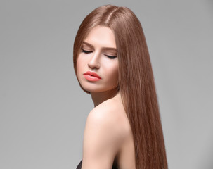 Attractive young woman with beautiful long hair on light background