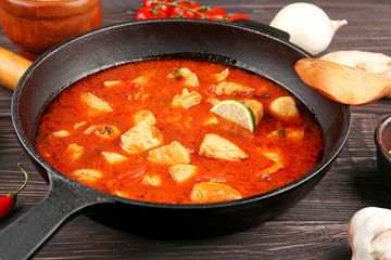 Chicken tikka masala in pan and ingredients on wooden table