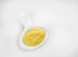 Creamy cheese in small modern saucer with comfortable handle, isolated on white