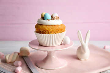 Cake stand with delicious Easter cupcake on wooden table