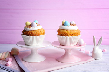 Cake stands with delicious Easter cupcakes on wooden table