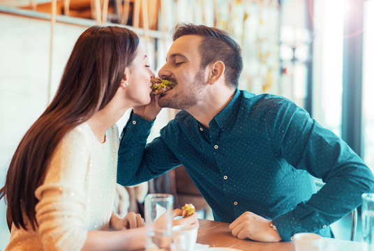 Beautiful young couple sitting in a cafe, having breakfast. Love, food, lifestyle