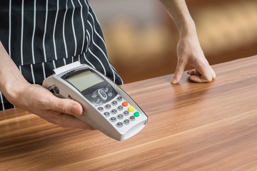 Seller holds payment terminal in hands.