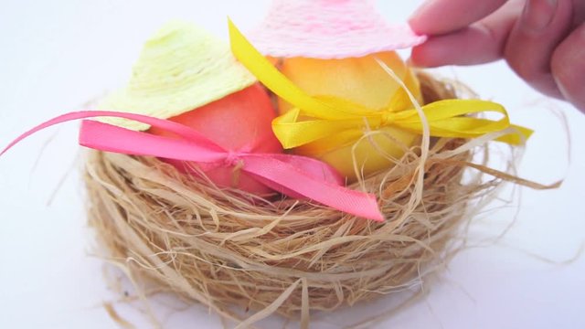 Easter eggs in straw nest are wrapped with colored ribbons