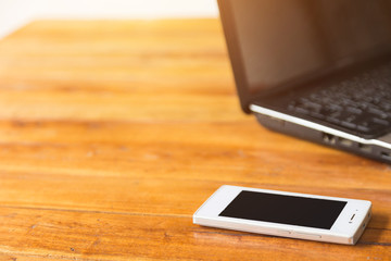 Desktop Mix of office supplies and gadgets . desk with laptop , Smart Phone, glasses , Watch , notebook , tablet, On a wood table.