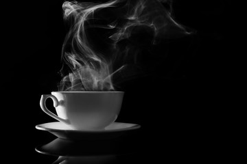 Steaming cup of coffee on black background