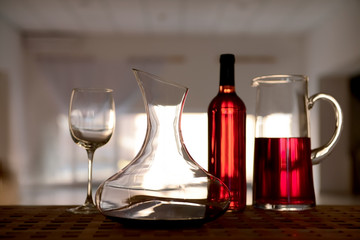Decanter with red wine and glass on table against blurred background
