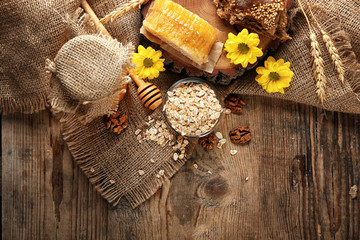 Composition with oatmeal, bread and honeycomb on wooden background