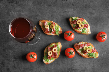 Obraz na płótnie Canvas Tasty bruschetta served with wine on gray background
