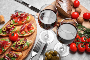 Tasty bruschetta served with wine on gray background