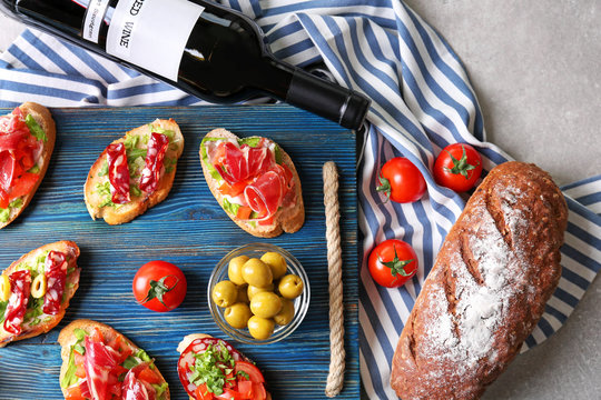 Wooden board with tasty bruschetta and  wine on light background