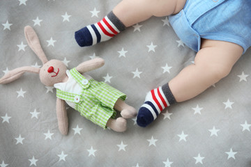 Cute little baby with bunny toy lying in cradle at home