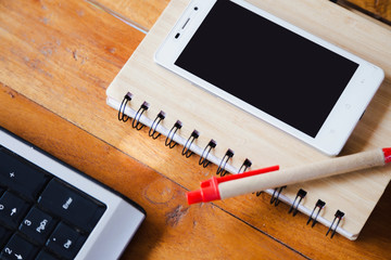 Desktop Mix of office supplies and gadgets . desk with laptop , Smart Phone, glasses , Watch , notebook , tablet, On a wood table.