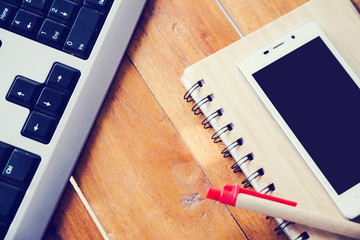 Desktop Mix of office supplies and gadgets . desk with laptop , Smart Phone, glasses , Watch , notebook , tablet, On a wood table.