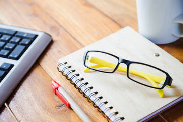 Desktop Mix of office supplies and gadgets . desk with laptop , Smart Phone, glasses , Watch , notebook , tablet, On a wood table.