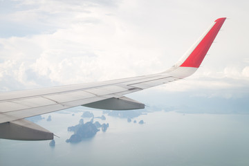 Wing of an airplane flying above the ocean and many island.