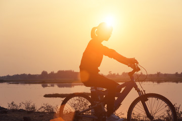 Fototapeta na wymiar Silhouette biker-girl at the sunset on the meadow