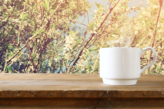 Cup of coffee a wooden table in front of spring landscape
