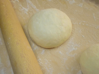 dough and flour on a wooden board, a rolling pin and a towel