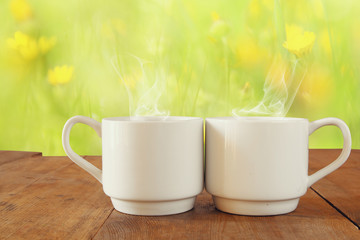 Two cups of coffee a wooden table in front of spring landscape