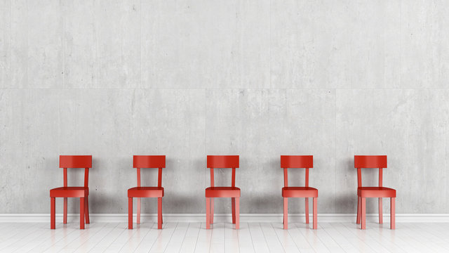 Five red chairs in front of a concrete wall