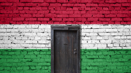 Hungary flag on brick wall. Closed door in a wall