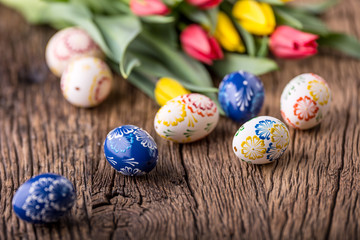 Easter. Hand made easter eggs and spring tulips on old wooden table.