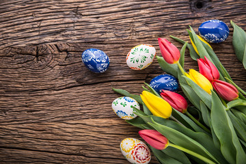 Easter. Hand made easter eggs and spring tulips on old wooden table.