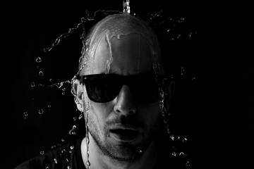 Portrait of a man being thrown water in the face against a black background