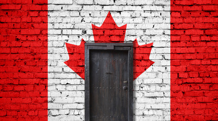 Canada flag on brick wall. Closed door in a wall