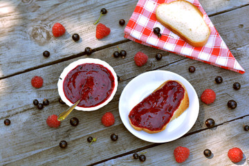 Top view of delicious, blended raspberry and black currant jam on white bread near red napkin
