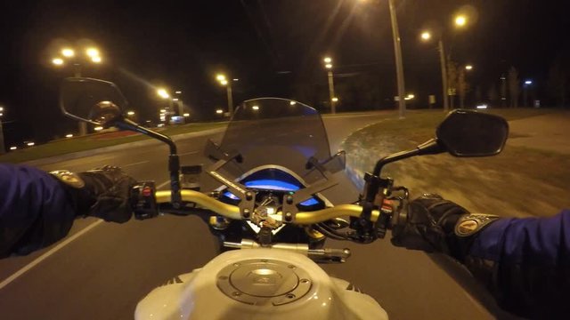 Point Of View Of A Motorcycle Rider Rides In Evening Town Road In High Speed. The Viewpoint Of Motorcyclist Driving In The Night Empty City Streets. Pov Close Up