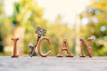 alphabet wood "I can" word on tree bokeh background, selective and soft focus