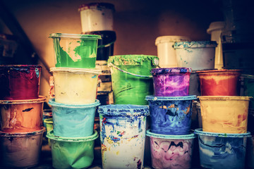 Buckets of liquid paint standing in a workshop.