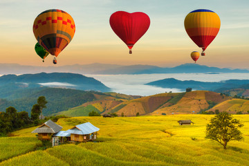 Fototapeta na wymiar Colorful hot air balloons flying over green terraced rice field in pa pong piang at Mae Chaem, Chiang Mai Province, Thailand