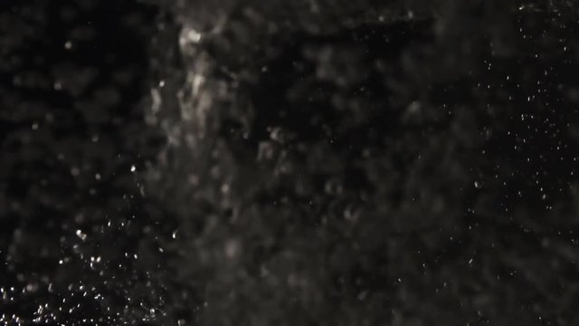the water flows closeup and lots of bubbles on a black background in slow motion