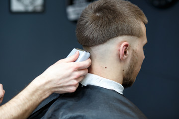 Obraz premium Great time at barbershop. Cheerful young bearded man getting haircut by hairdresser while sitting in chair at barbershop