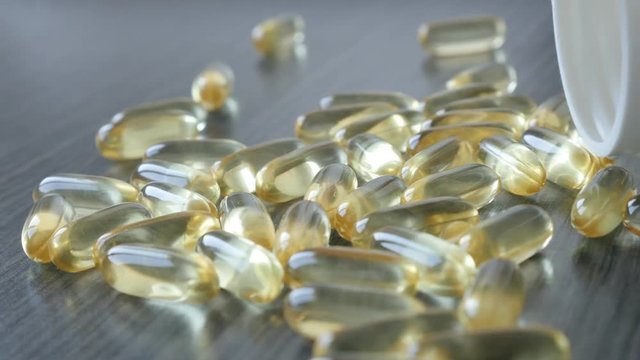 Yellow medicines on wooden table slow pan 4K 2160p 30fps UltraHD footage - Transparent omega 3 fish oil soft gel capsule