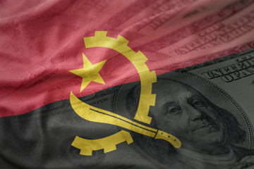 colorful waving national flag of angola on a american dollar money background.