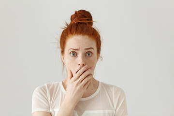 Scared and shocked bug-eyed pretty girl with orange hair having surprised and astonished facial...