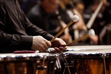 Naklejka premium Hands musician playing the timpani in the orchestra closeup in dark colors
