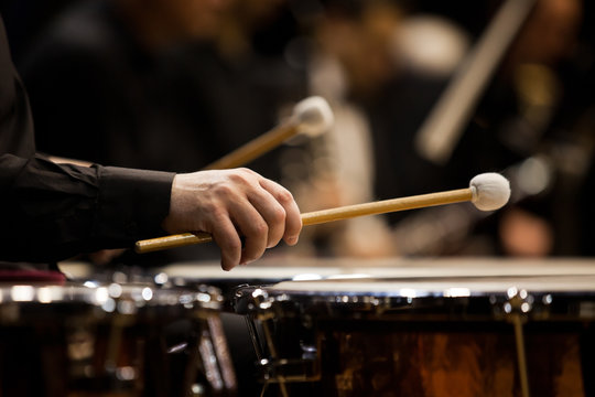 Hands musician playing the timpani in the orchestra closeup in dark colors