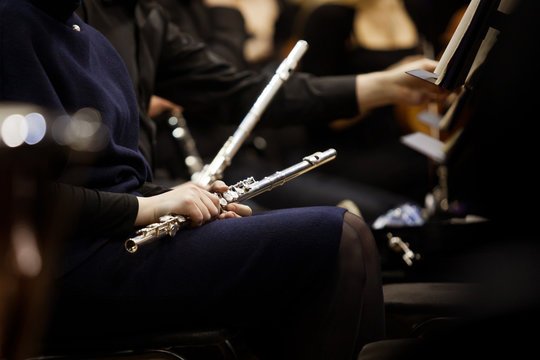 Flute in the hands of a woman in an orchestra in dark tones