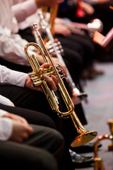 Obraz na płótnie Canvas Hands of a musician holding a trumpet in an orchestra closeup