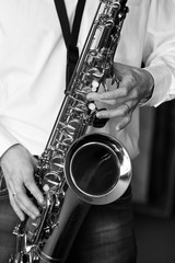 Obraz premium Saxophone in the hands of a musician of a closeup in black and white
