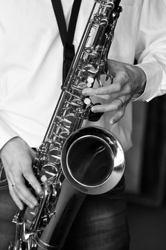 Saxophone in the hands of a musician of a closeup in black and white
