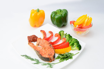 Grilled red fish with sauce, broccoli, parsley and dill  on a white plate
